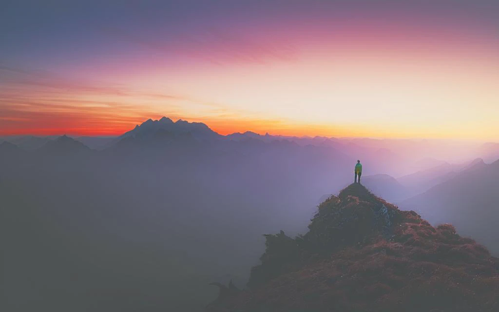 a person standing on top of a mountain at sunset