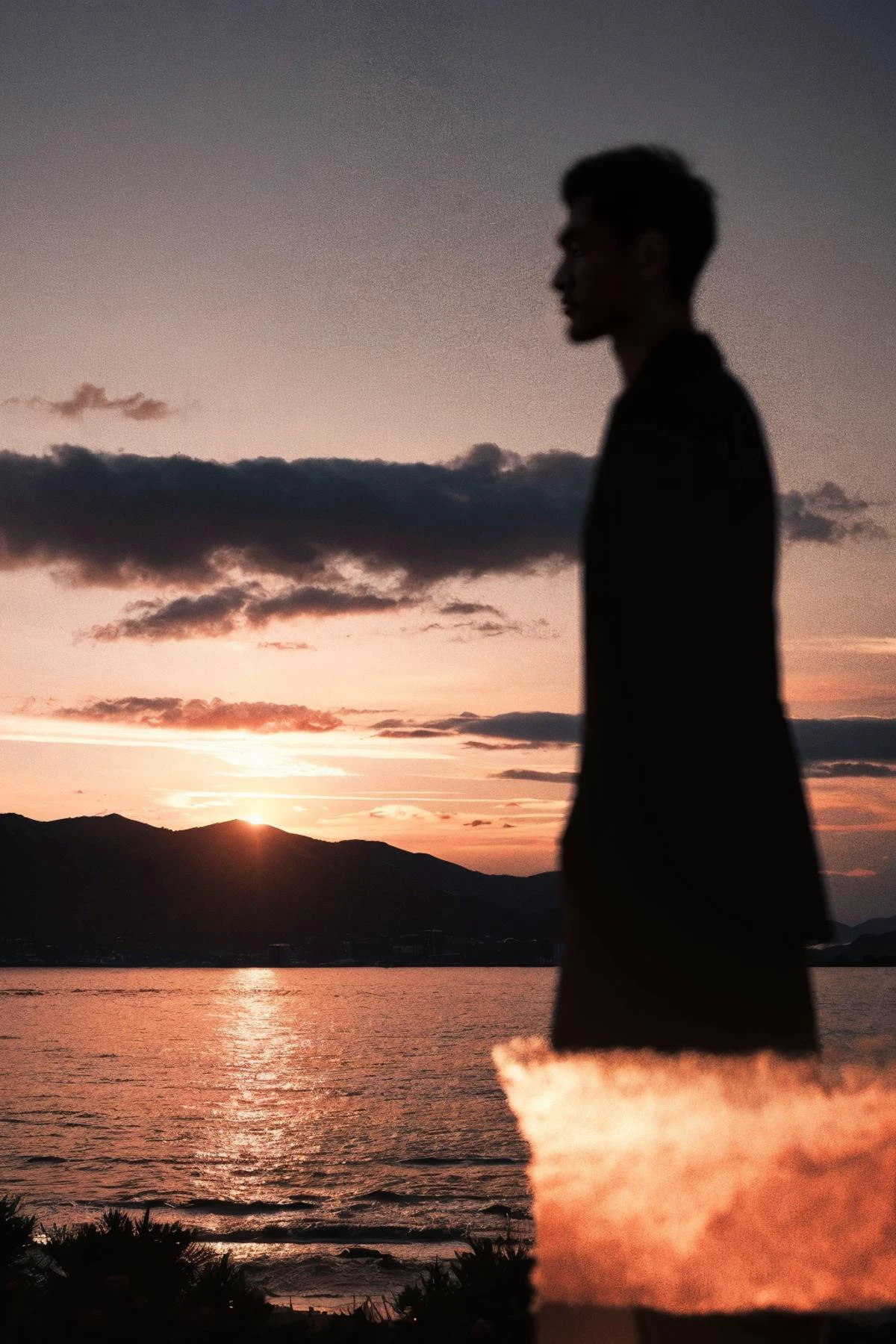 A blurred figure stands against the backdrop of a sunset-drenched landscape, lost in the grandeur of the moment. The heavens above transition from day to night in a symphony of color, and the silhouette of the man is cast as an introspective shadow on the threshold of nightfall, embodying the transient beauty of lifeâs simple pleasures.