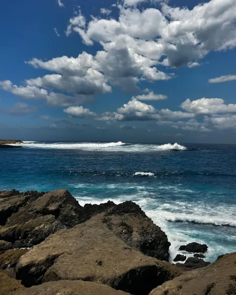 score_9,score_8_up,score_7_up,
a breathtaking coastal scene. The sky is clear with a few scattered clouds, and the ocean is calm, with waves gently crashing against the rocky shore. Two prominent rock formations rise from the water, with one on the left and the other on the right. The rocks are covered in vegetation, suggesting they might be part of a larger landmass or island. The overall ambiance of the image is serene and picturesque, capturing the beauty of nature.