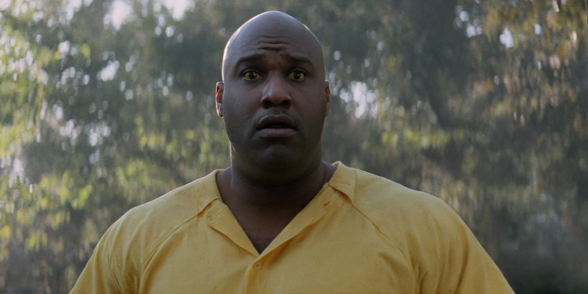Horror-themed, <lora:Fright Night 1985 Film Style:1>
Cinematic Medium Shot Film Footage captured by Panavision Cameras and Lenses, a Bouncer a big black bald man in a yellow shirt is holding his hands together with a surprise look on his face, Fright Night 1985 Film Style, Eerie, unsettling, dark, spooky, suspenseful, grim, highly detailed