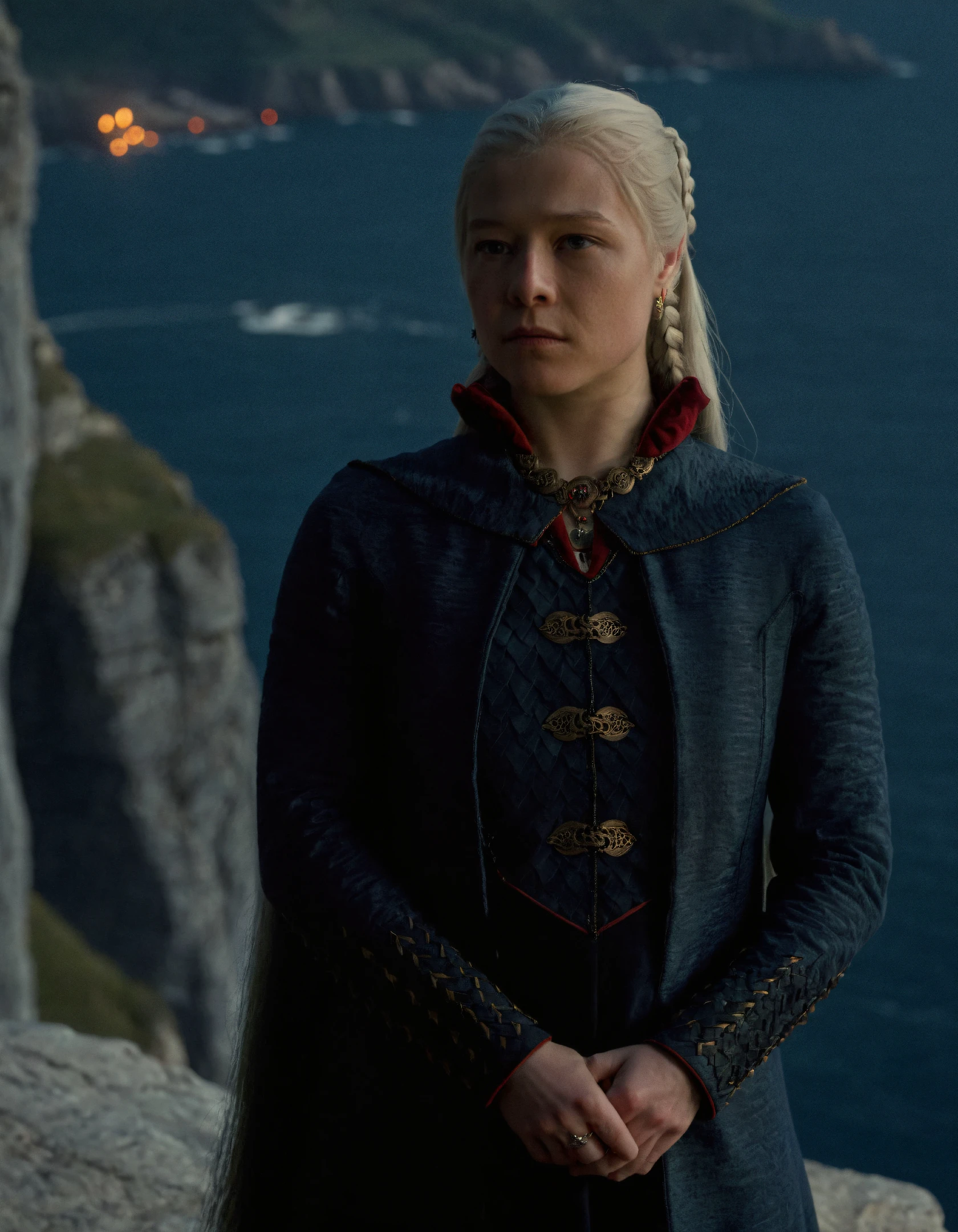 super high resolution photo,upper body shot of rha3nyra,she has a long braid white hair ponytail,she is wearing a blue coat and necklace and she is standing near a cliff,super detailed background,depth of field,(sweaty skin:1.2),volumetric lighting,during night,a lot of torches are illuminating the surrounding,dimly lit,(surreal dramatic lighting shadow),natural lighting
