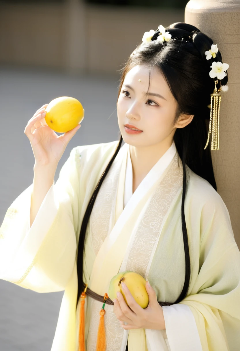 a young woman, presumably of East Asian descent, wearing traditional Chinese attire. She has long, dark hair adorned with white flowers and is seen holding a yellow fruit, possibly a melon or a pear, close to her face. The fruit has a tassel attached to it. She is wearing a light-colored blouse with floral patterns and a dark-colored sash. The background appears to be an outdoor setting with a textured surface, possibly a stone wall or a rocky terrain.