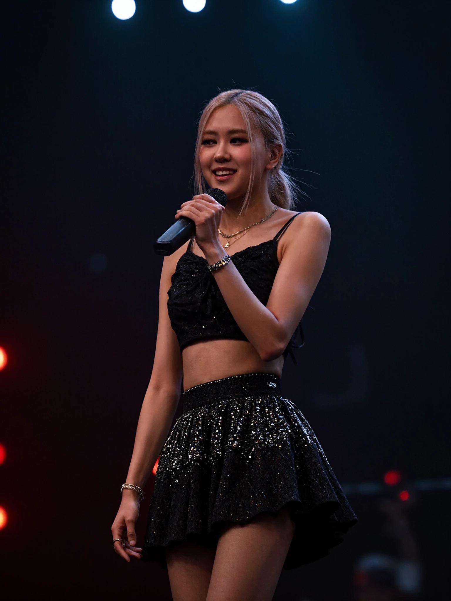 Portrait of blaros woman performing on stage. She is wearing a black and silver skirt and top. She is holding a microphone. 