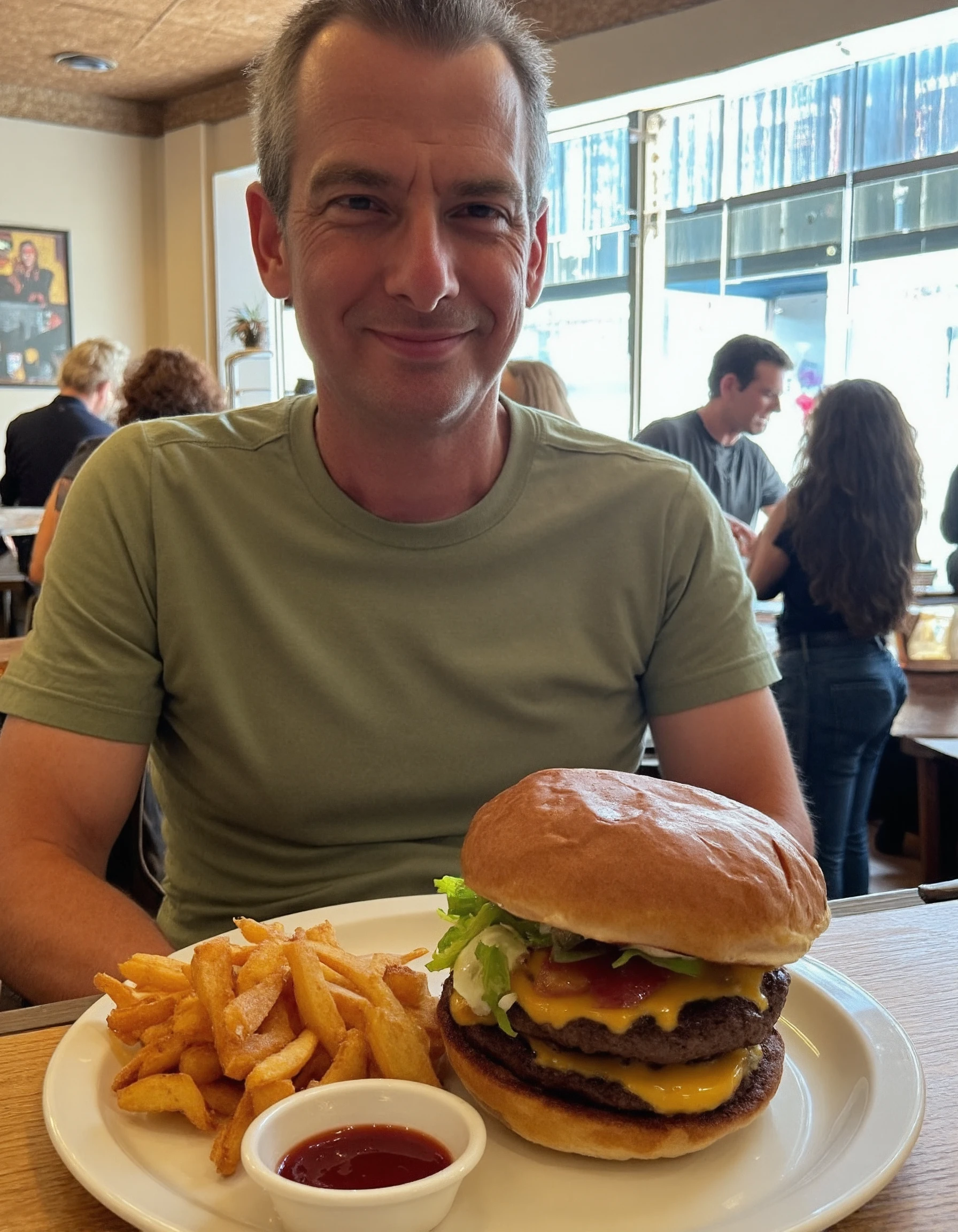 43stet1c A man is sitting at a table in a restaurant, casually dressed in a t-shirt. In front of him is a burger on a white plate, stacked with a thick beef patty, melted cheese, lettuce, tomato, and a toasted bun. A side of fries sits next to the burger, along with a small dish of ketchup. The restaurant has a cozy atmosphere, with warm lighting, wooden tables, and other patrons visible in the background, engaged in conversation. Thereâs a decorative plant on the table, and behind him, a large window allows natural light to pour in, with a view of the street outside. <lora:Aesthetic_Amateur_Photo_V4_Beta_2:1.2>