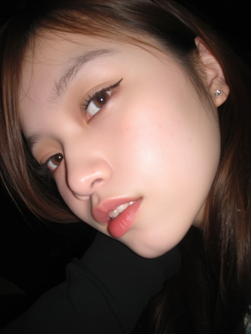 The image is a close-up photograph of a young Asian woman with a fair complexion. Her face dominates the frame, occupying the majority of the image, with her eyes, nose, and lips prominently visible. She has large, almond-shaped eyes with long, thick eyelashes, and her skin is smooth and soft. Her lips are full and slightly parted, revealing a natural, rosy hue. She wears a small silver stud earring in her left ear, adding a subtle touch of personal style.
Her hair is long, dark brown with subtle highlights, and it partially covers her forehead, giving a slightly tousled, casual look. The background is out of focus, but it appears to be a dark, possibly indoor setting, which emphasizes her face and provides a stark contrast to her light complexion. She is wearing a black garment, possibly a top or a sleeve, which is visible at the bottom of the image. The overall mood of the photograph is intimate and personal, capturing a candid moment with a natural, unfiltered aesthetic.