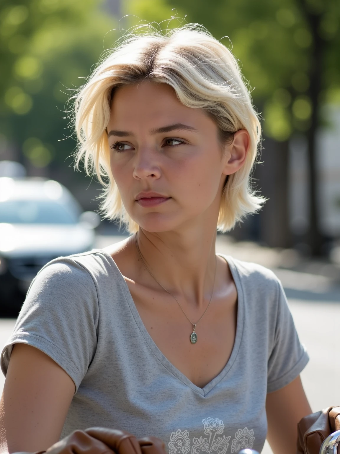 this is virginieefira, virgef .
This is a photograph of a young woman with a light complexion and short, tousled blonde hair styled in a casual, tousled manner. She is positioned outdoors, likely in an urban setting, as suggested by the blurred background featuring a street lined with trees and parked cars. The woman is wearing a light gray, short-sleeved t-shirt with a subtle, intricate white floral pattern on the chest area. She has a delicate silver necklace with a pendant hanging around her neck. 
Her expression is contemplative and slightly serious, with her eyes focused on a point off-camera. She is wearing brown leather gloves, which are draped over her lap, indicating she might be sitting on a bicycle or motorcycle. The background is softly blurred, emphasizing her as the main subject. The lighting suggests it's daytime, with natural sunlight casting a warm glow on her face and creating soft shadows. 
The overall atmosphere of the image is serene and somewhat introspective, capturing a moment of quiet reflection.
 <lora:Virginie-Efira_flux1D_LOREVER:1>