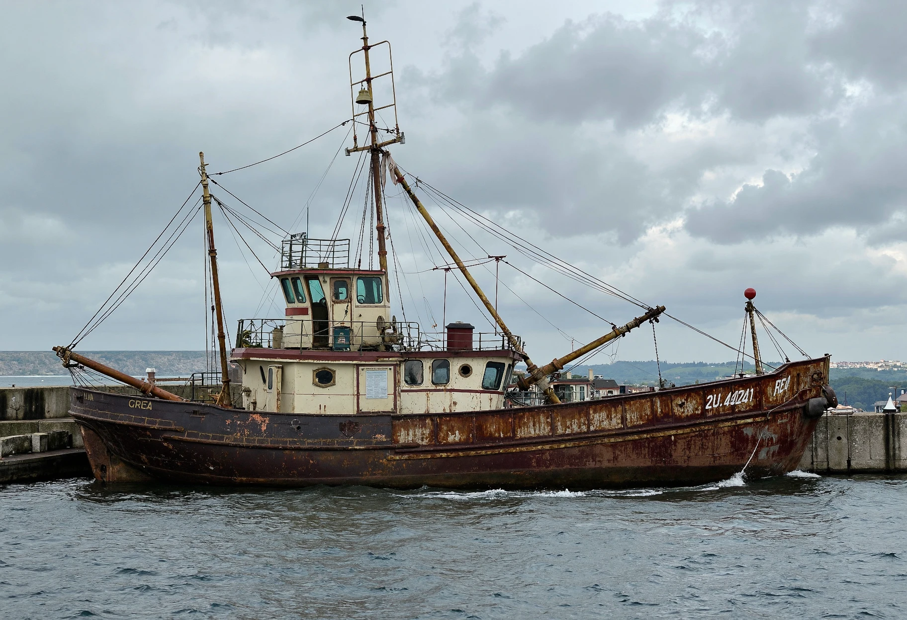 GRUNGE, side view of an old fish trawler on a cloudy day in a port