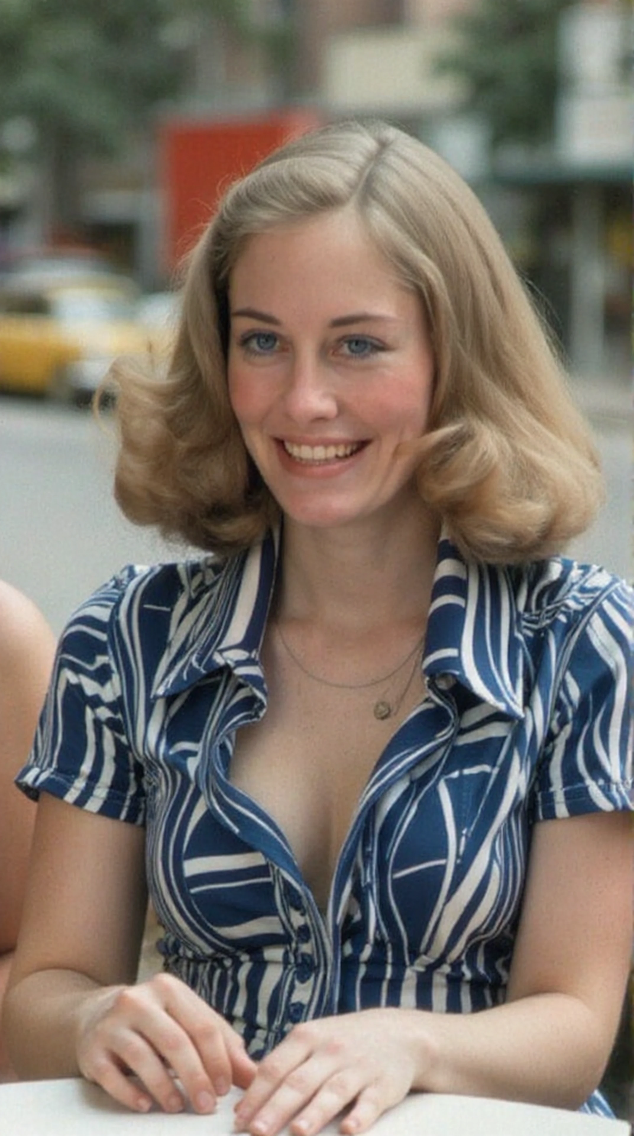 close-up photo of woman, upper body, sitting at a sidewalk cafe in 1970s NYC, she is laughing with a friend, she wears a blue and white 1970s colorful polyester dress. Detailed, intimate, clear, personal