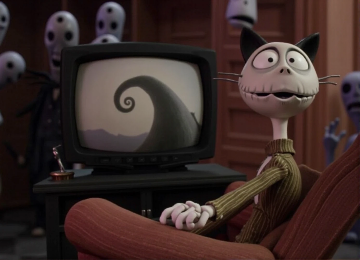 Stop motion film showing cat puppet sitting on a couch by the tv in style of Tim Burton. Nightmare before Christmas movie. Some monsters at background. Felix the cat with cat ears and whiskers