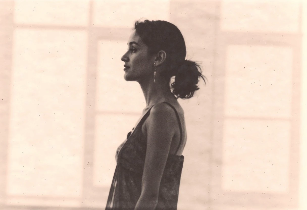 an aesthetic, minimalist depiction of a female profile in side view. The focus is on the soft contours and calm, monochromatic tones. The scene feels mystical and dreamy, almost as if viewed through a delicate mist, with gentle light accentuating the silhouette. The background is diffuse and creamy white, drawing attention to the elegant simplicity of the figure.