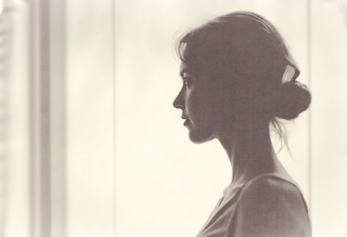 an aesthetic, minimalist depiction of a female profile in side view. The focus is on the soft contours and calm, monochromatic tones. The scene feels mystical and dreamy, almost as if viewed through a delicate mist, with gentle light accentuating the silhouette. The background is diffuse and creamy white, drawing attention to the elegant simplicity of the figure.