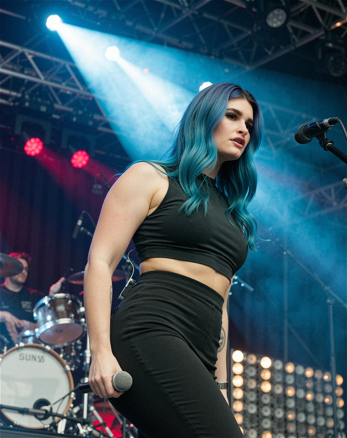 low-angle photo of Courtney LaPlante with blue hair, she is looking down at the viewer from the stage, microphone in her hand down by her side. This shot was taken with a Sony A7III, a 50 mm lens. RAW photo, award-winning photograph