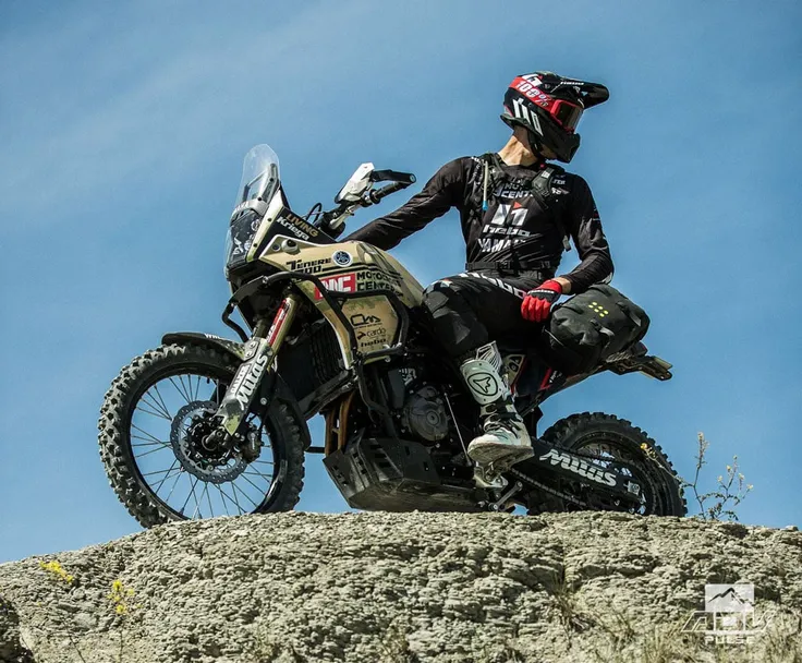 arafed motorcyclist sitting on a dakar motorbike in the backcountry, big windscreen, mud dirt tyres, one exhaust, no luggage,Yamaha, yellow fairing, stopped, rear luggage, rider with enduro boots and helmet, motorbike with decals, skid plate