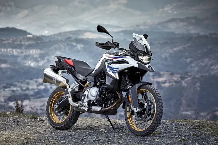 Standing alone arafed adventure motorcycle with mountains background, big windscreen, mud dirt tyres, one exhaust, bmw