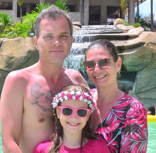 casal com filha de oculos escuro belos tracos, fundo cascata montanha