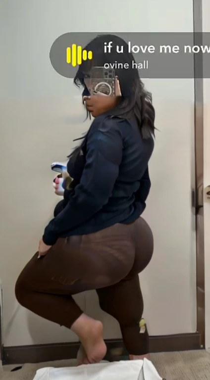 woman in tight brown pants taking a selfie in a mirror, thicc, thick thigs, big booty, thick, pawg, toned derriere, tight outfit, bending over, thick thighs, curvy accentuated booty, thick body, she is facing the camera, exposed thighs!!!, thick tail, boot...