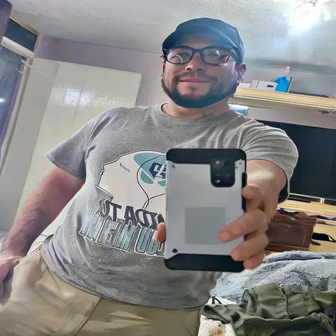 there is a man taking a selfie in a mirror, very accurate photo, wearing a tee shirt and combats, phone!! held up to visor, cell phone photo, selfie of a man, very very low quality picture, selfie!!!!! of a man, he is holding a smartphone, outfit photo, 8k...