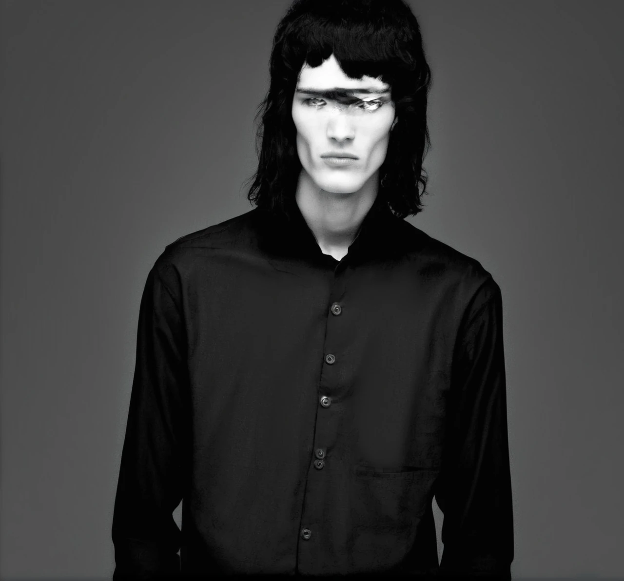 A tall, black-clothed, white young man with black hair and white eyes 