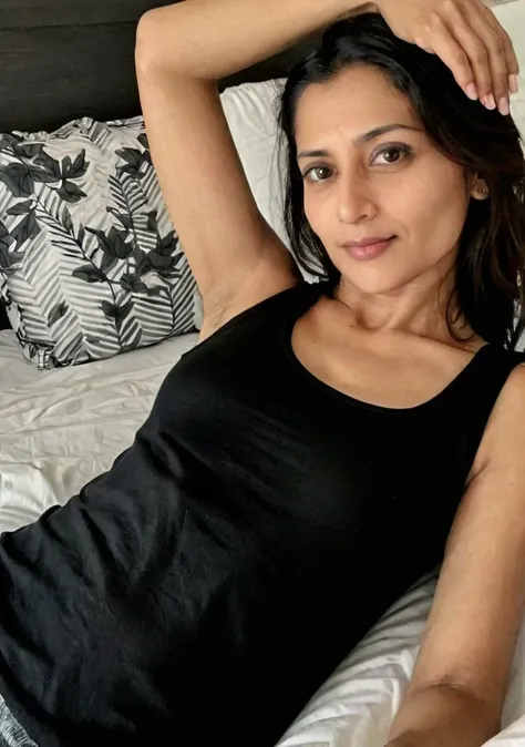 selfie in the dark, pretty indian innocent mature mother, fair white skin, lying in bed, in a black tank top,