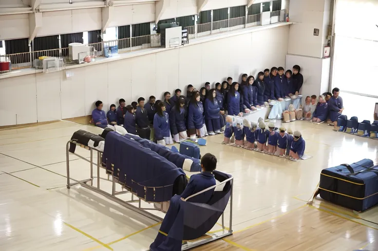 A female student in a sailor uniform is watching a physical education class in the gymnasium because she is feeling unwell