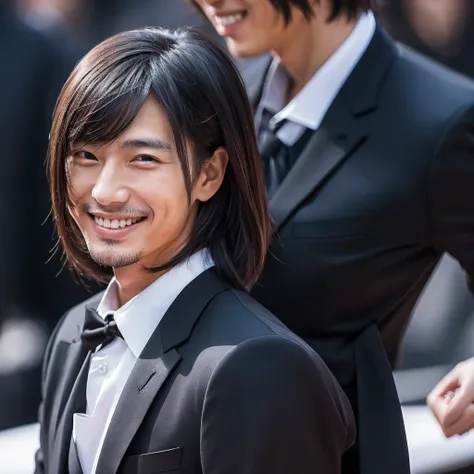 A handsome Japanese man with Japanese hair and a black suit is smiling with a closed-mouthed, ageless smile.