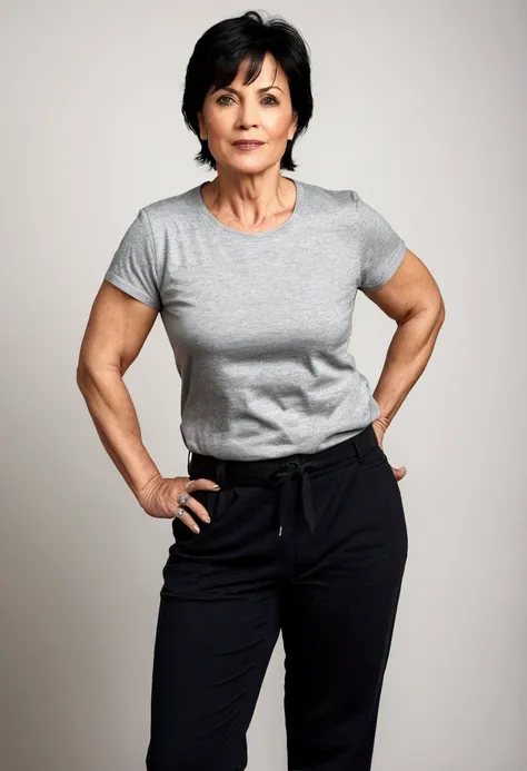 A woman around 45 years old, with a sturdy build but not overweight, short black hair. She is wearing pants and a t-shirt. The image shows her full body.