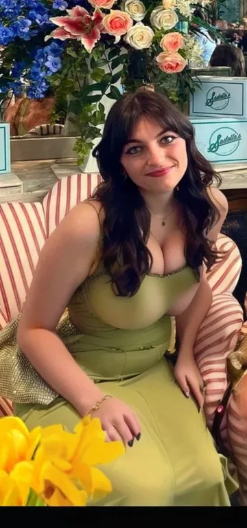 there is a woman sitting on a couch with flowers in the background, pretty female phoebe tonkin, lucy hale, phoebe tonkin, by Emma Andijewska, christina kritkou, kaitlyn michelle siragusa, joey king, green dress, profile photo, very very low quality pictur...