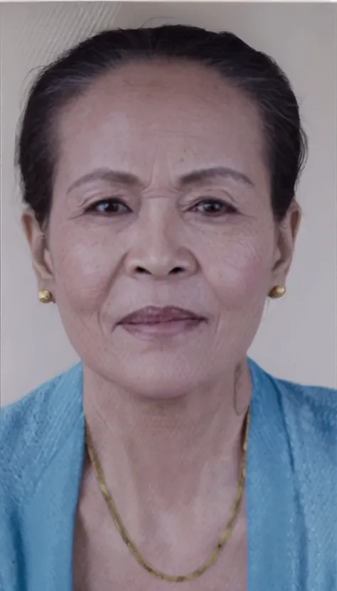 there is a woman with a necklace on her neck and a blue shirt, photo of a woman, taken in the early 2020s, portrait 6 0 - year - old woman, 60 year old woman wearing traditional Balinese kebaya, black earrings, gold necklace