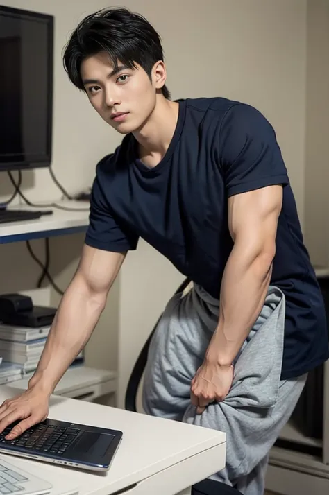 a young asian man stands, handsome, muscular, looking at the camera. in a simple navy blue t-shirt., in the computer room