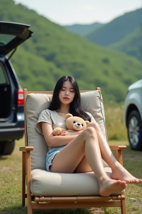 "Horizontal format photo showing a young woman relaxing on a cushioned outdoor lounge chair. She has long black hair and is wearing a light beige top with light denim shorts. She is barefoot, with one leg resting on the cushion and the other foot slightly ...