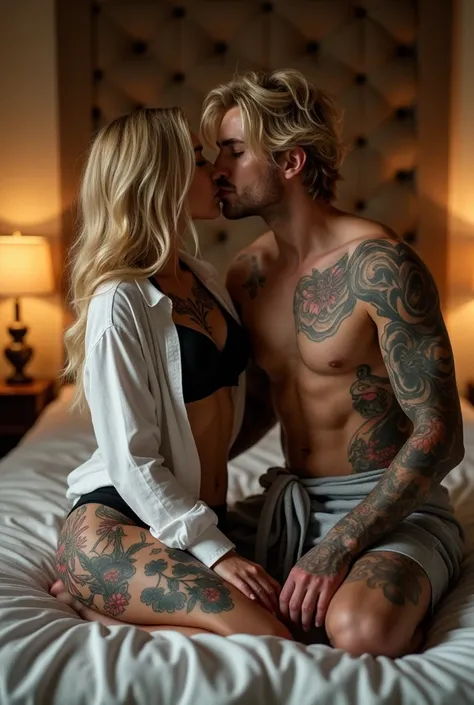 A couple kissing on their knees on top of the bed facing each other, a blonde woman wearing a long-sleeved shirt, with one side falling over her shoulder showing her black bra, and all the tattoos she has. A shirtless man with blonde hair showing off all h...