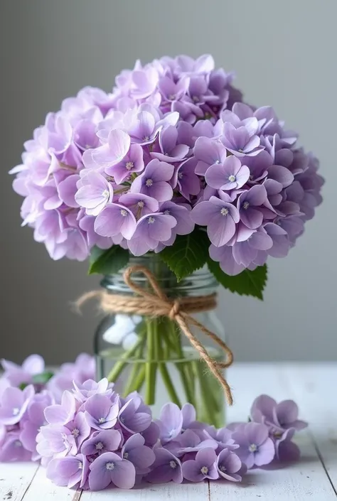 This image is、Shows a stylish glass jar with beautifully decorated purple hydrangea flowers。The bottle is wrapped with hemp string.、It creates a natural atmosphere。The flowers are pale purple、Some flowers are open。There are lots of flowers around the toile...