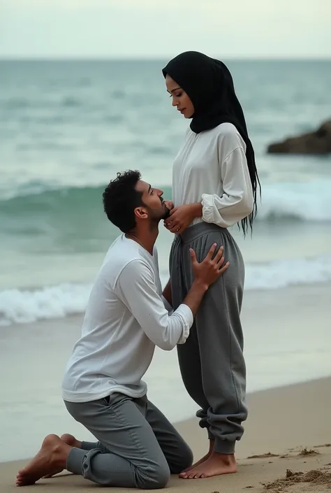 Black headscarf on the beach, white long sleeve t shirt, baggy grey sweatpants, barefoot, Sexy skinny woman. He kneeled before the woman, Man kissing front of woman&#39;s sweatpants. 