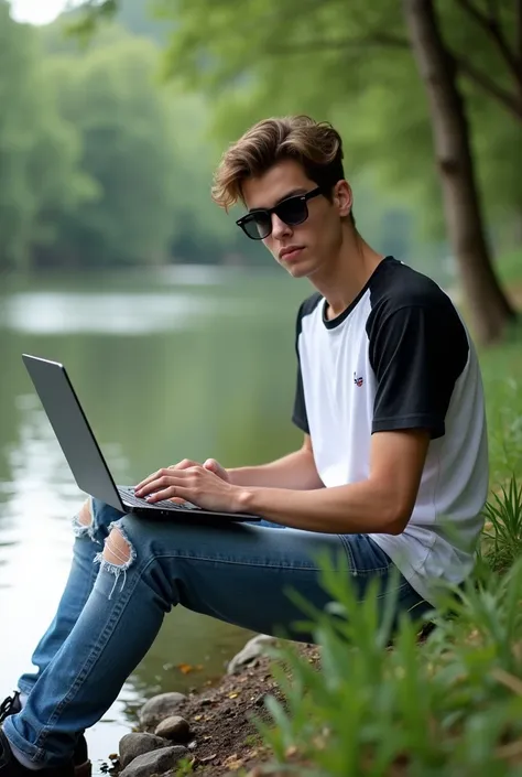 A 17 year man is sitting by the river with a laptop in ripped pants and a white and black shirt with sunglasses looking me. Realistic photo 