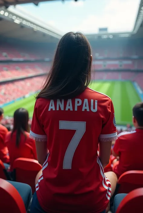 A girl sitting with her back turned in a stadium wearing a Real Madrid shirt that says Anapau and the number 7 with her hair down