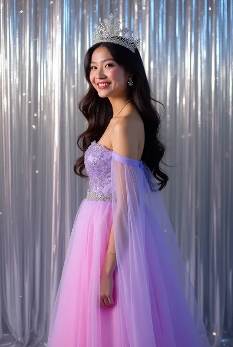 A woman in a lilac and pink party dress standing sideways with one arm visible and looking straight ahead in front of a silver curtain with long wavy hair wearing a silver crown smiling and happy with her hands extended downwards well lit with a non-Asian ...