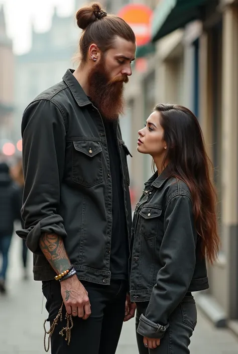 Un homme très grand aux cheveux chatins attacher en chigon ,une barbe fournie avec des piercing et un style skater. A ses côtés une femme petite brune avec de longs cheveux et un style steet wear