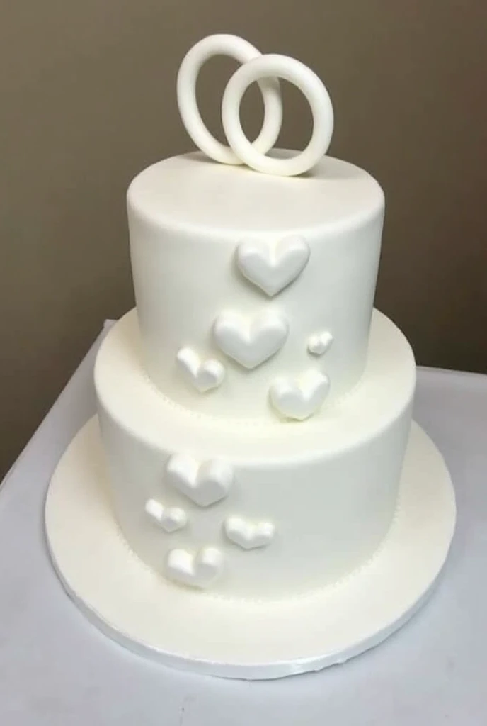 Two-tier white cake , with hearts on the first floor and two rings on the upper floor