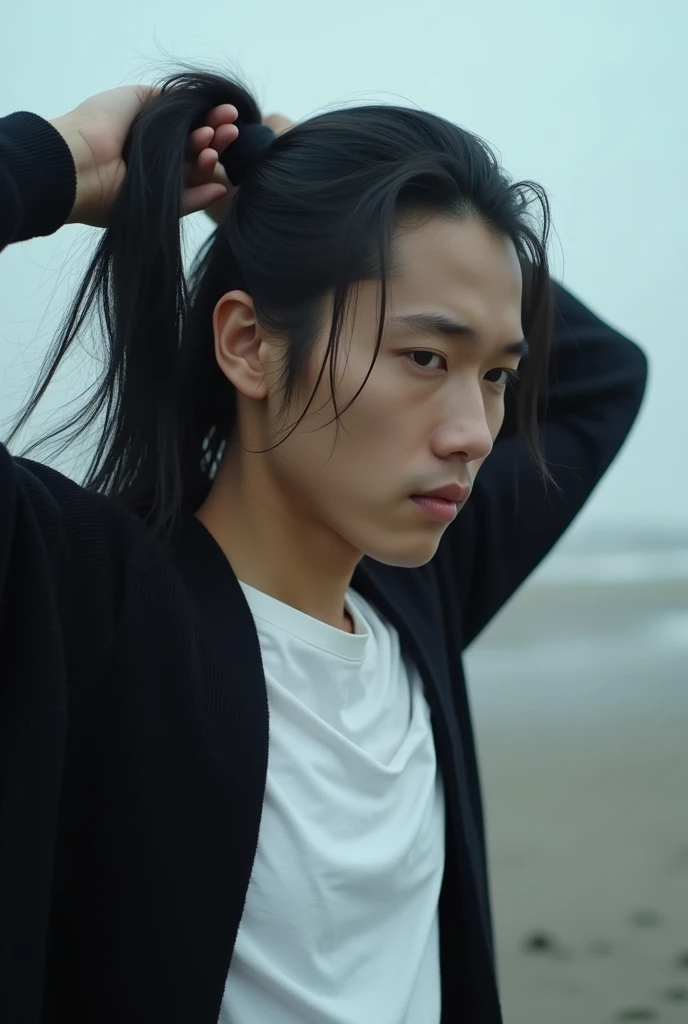 4k, Realistic, Photography, high detailed, close up detail of a handsome Asian man with long black hair,is tying her hair into a ponytail style,her lips bit a small short rope ,background of a blurred beach,ghotic,white t-shirt,with a black cardigan as out...