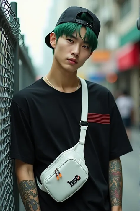 A very handsome Korean man with short green hair, wearing a snapback hat, leans against a metal fence in an urban setting. He wore a black t-shirt with red stripes, equipped with a small white sling bag with the "HSC" logo tied across his chest. He stared ...