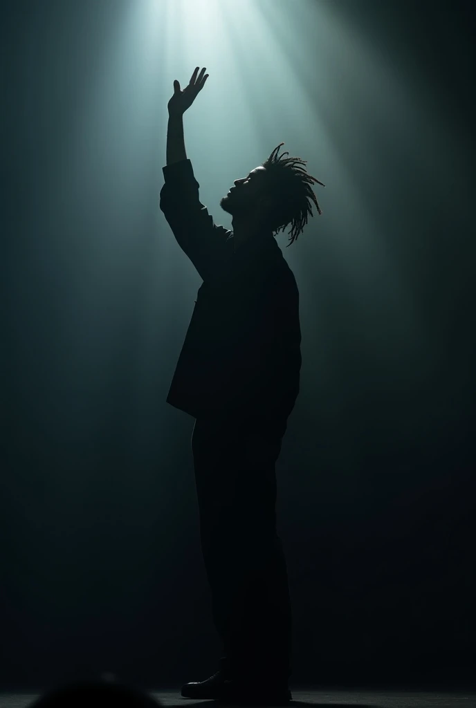 A slim male short dreadlocks musician shadow lifting his hand to worship God on stage 