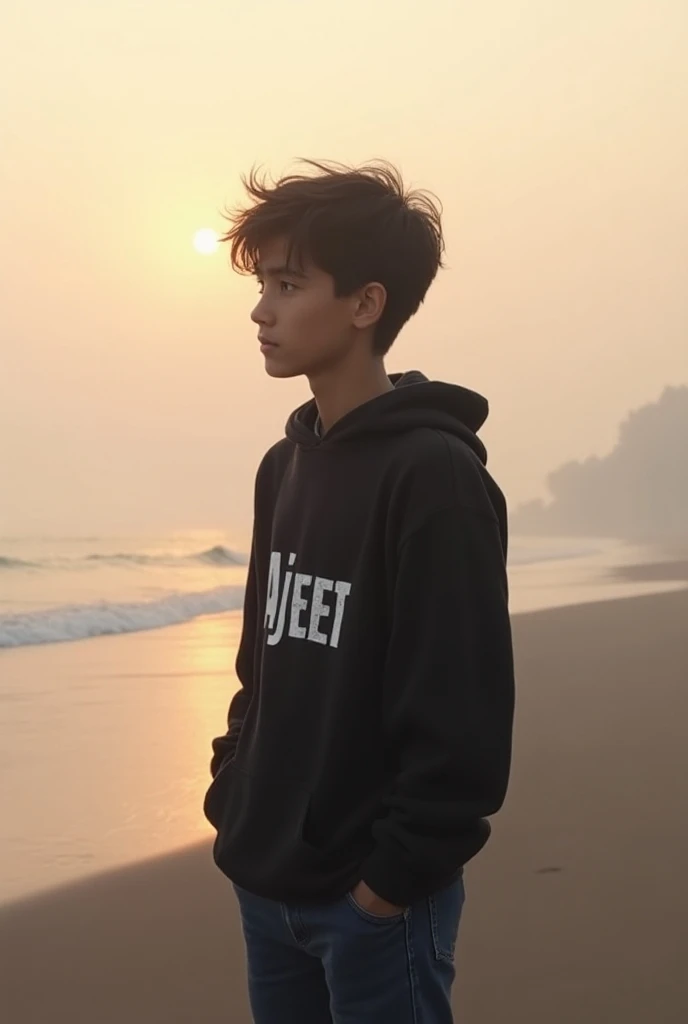 Create an image of a young boy standing alone on a quiet, misty beach at sunrise. And his wearing black t-shirt the boys t-shirt has the name " AJEET "written in deep white letter The boy is around 20years old, wearing a simple hoodie and jeans, his hair t...