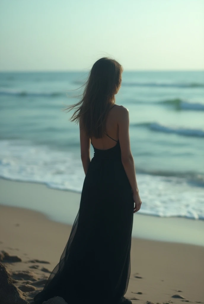 The womans face is not visible as she looks back at the beach.