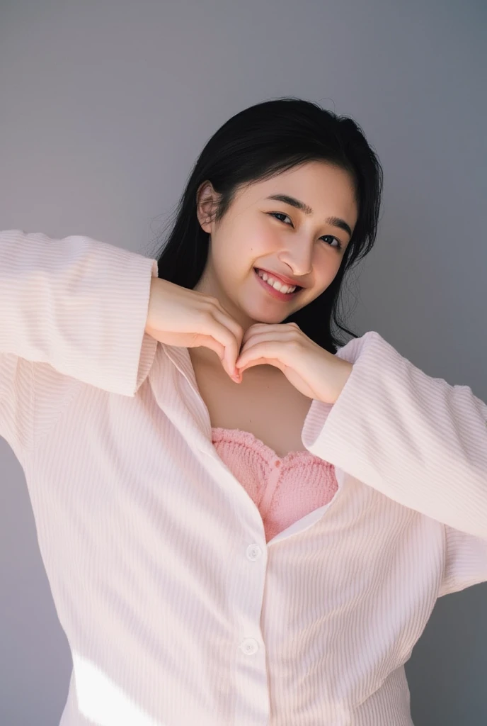 Only one woman with a cute smile wears cute, fluffy off-shoulder pajamas, makes a big heart shape with both hands, and poses them in front of her chest, View above collarbone、The background is a monotone 

