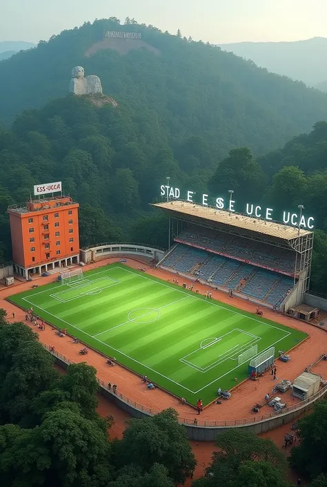 Un stade de football que les ouvriers sont entrain de construire dans une forêt avec le gazon déjà  achevé le stade qui est en finition des travaux au haut du stade il y’a une plaque lumineuse écrit     STADE DE L’ESS UCAC et à côté du stade il y’a un gran...