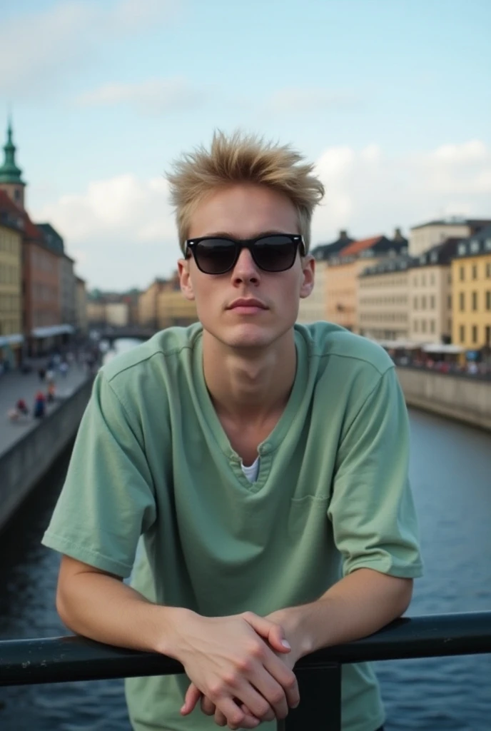 a guy in a light green shirt with blond hair and black sunglasses leaning with his hands on a bridge in Stockholm