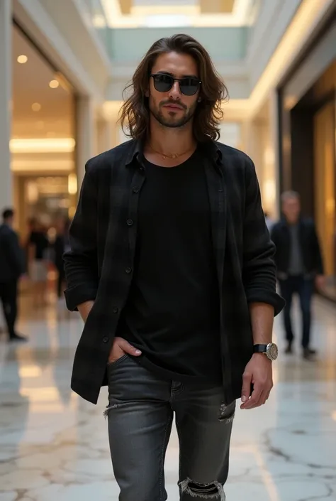 A handsome man with long hair wearing black rayban glasses wears a black jersey tshirt and a flannel shirt inscribed Deep Black and wears ripped jeans walks inside a luxury mall