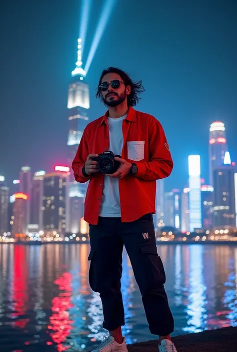 
A man stands in front of a city view at night. He is wearing a bright red shirt with a white pocket on the chest, combined with a white shirt as an inner. Black cargo pants and white shoes complete his appearance. This man holds the camera with both hands...