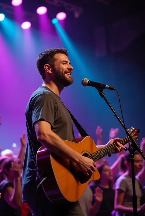 Photograph captured in a crowd during a concert, focusing on a man playing the guitar. He wears casual clothes and displays a genuine smile, clearly engaged and happy with the moment. In the background, the show stage is visible, illuminated by professiona...