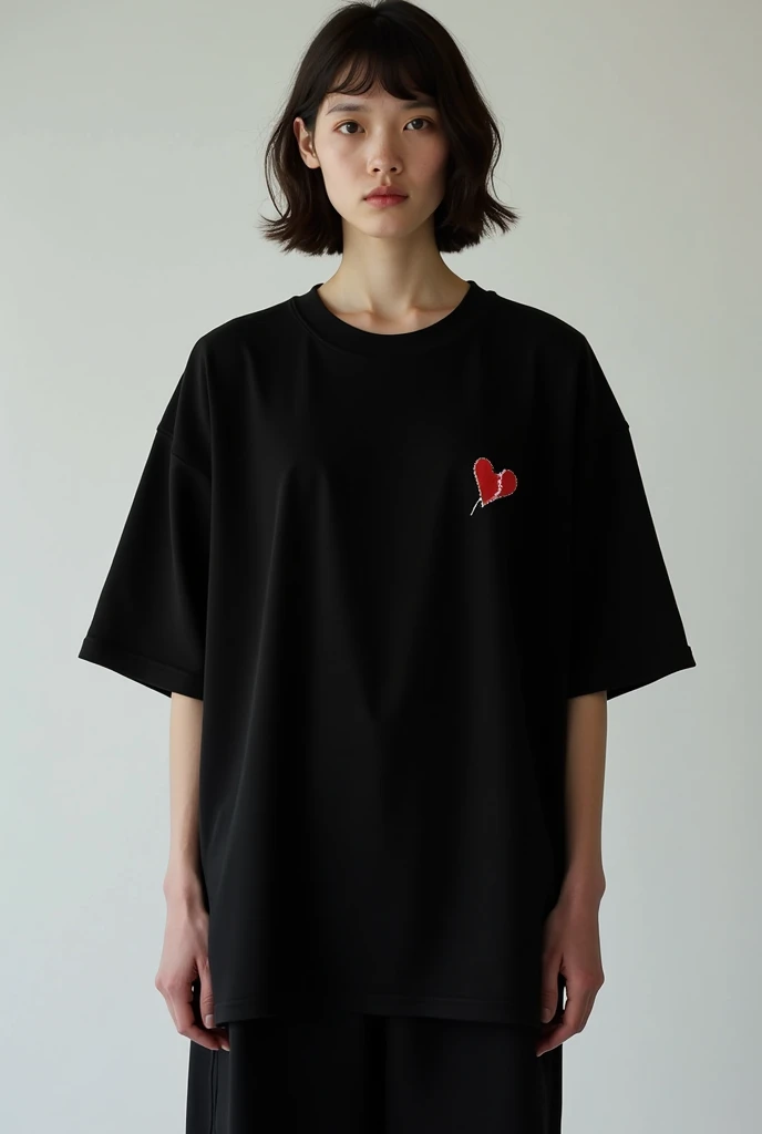 An oversized black short sleeve tee with a tiny red broken heart on the left side.
